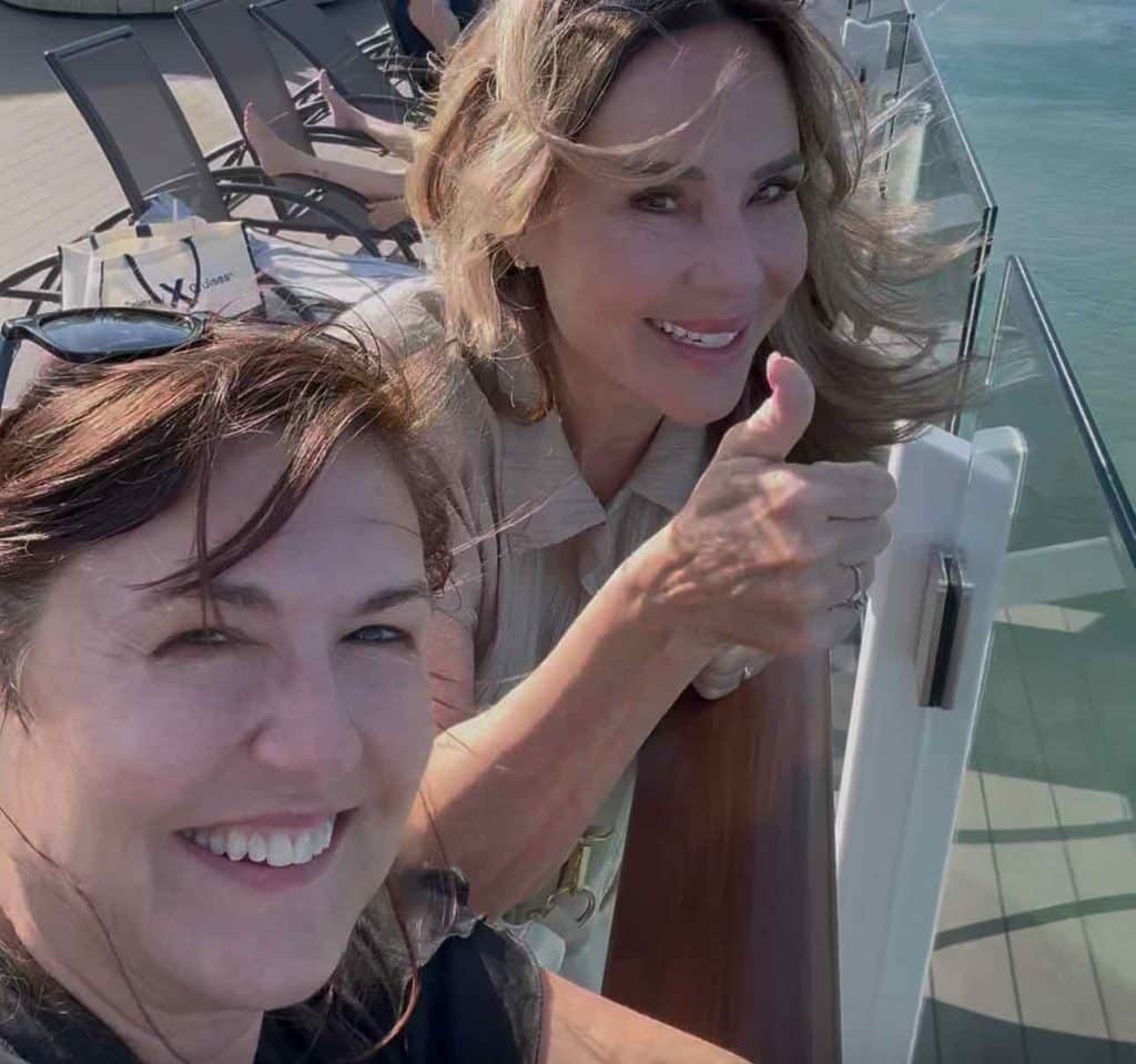 Two women over the age of 50 on a cruise deck enjoying the ocean air.