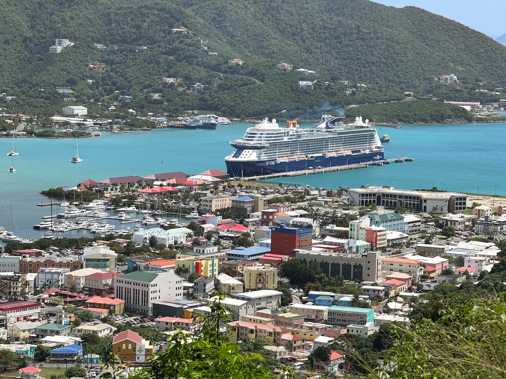 Celebrity ship, one of the best cruise lines for seniors, sits docked in the aquamarine waters of a caribbean port.