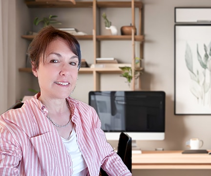 Kathleen Hesketh, travel agent/advisor dressed in red striped shirt, sits at her desk, ready to book travel
