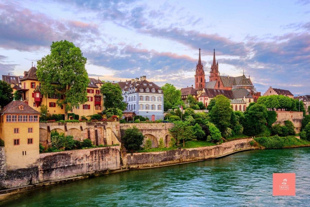 The blue green waters of the Rhine River flow in front of the town of Basel Switzerland, a scenic stop on most Rhine River Cruises.