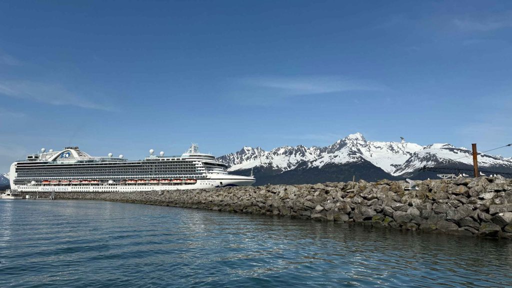 Princess Cruise ship sits docked on a port day with Alaska mountains in the background