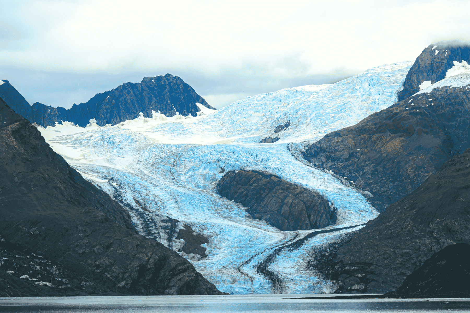A glacier makes its way down a hill to the fjord at Kenai Fjord National Park